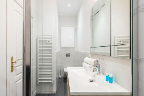 une salle de bain blanche avec un lavabo et un miroir dans l'établissement Promenade, 2pièces chic et clim avec terrasse, à Nice