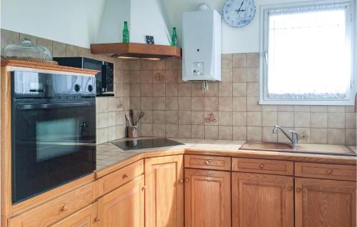 a kitchen with wooden cabinets and a black appliance at Two-Bedroom Holiday Home In La Tranche-Sur-Mer in La Tranche-sur-Mer