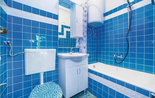 a blue tiled bathroom with a toilet and a sink at Stunning Apartment In Crikvenica With Wifi in Crikvenica