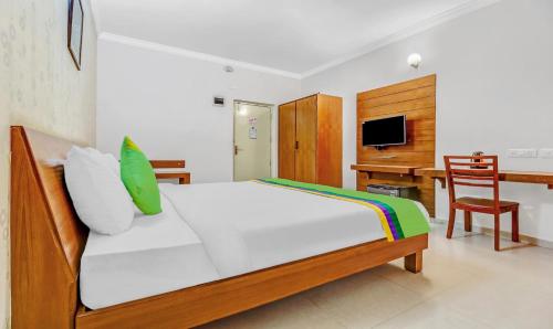 a bedroom with a bed and a desk with a computer at Treebo The Grand Skyla Marathahalli in Bengaluru