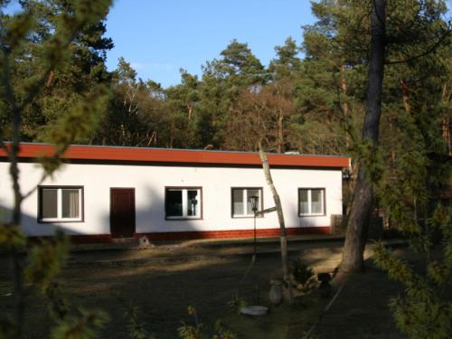 a white house with a red roof in the woods at Elite holiday home with garden in Spreenhage in Grünheide