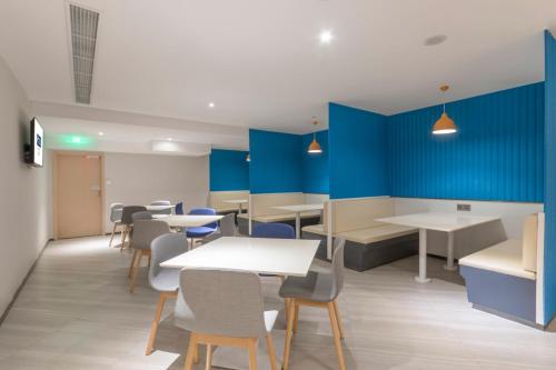 a dining room with blue walls and tables and chairs at Holiday Inn Express Shanghai Gubei by IHG in Shanghai