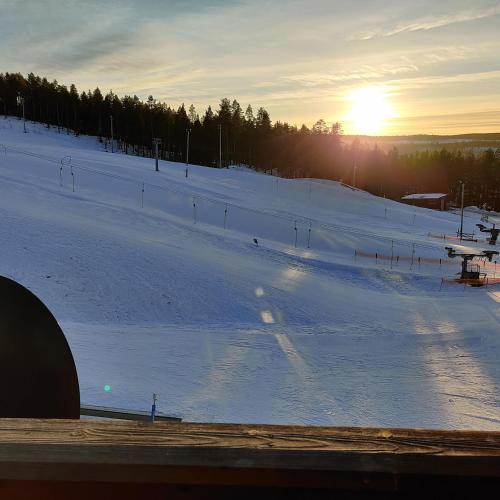 a snow covered ski slope with the sun in the distance at Hotell Tjamstan Malå in Malå
