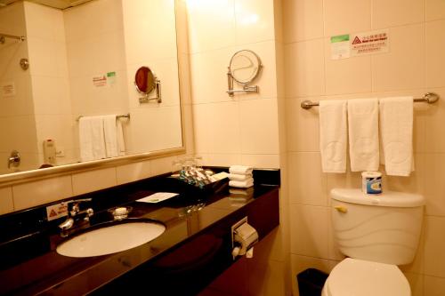 a bathroom with a sink and a toilet and a mirror at Jianguo Qianmen Beijing in Beijing