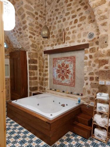 a bath tub in a room with a stone wall at Akka in ‘Akko