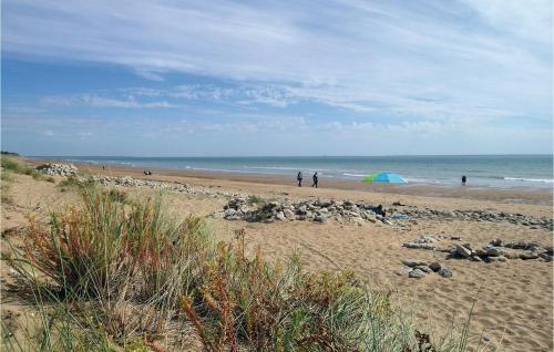 a group of people on a beach with an umbrella at Three-Bedroom Holiday Home In La Tranche Sur Mer in La Tranche-sur-Mer