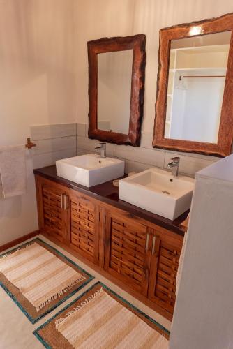 a bathroom with two sinks and a mirror at Bela Flor Beach Front Apartments in Inhambane