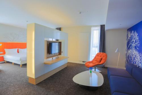 a room with a tv and a couch and a chair at IBIS Styles Ulaanbaatar Polaris in Ulaanbaatar