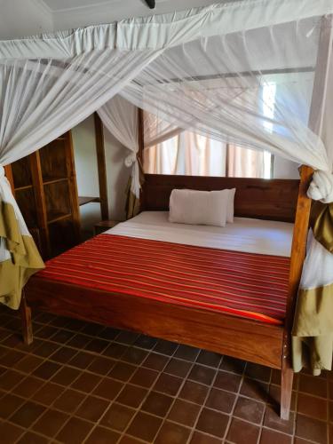 a bed with a canopy in a room at Honey Badger Lodge in Moshi