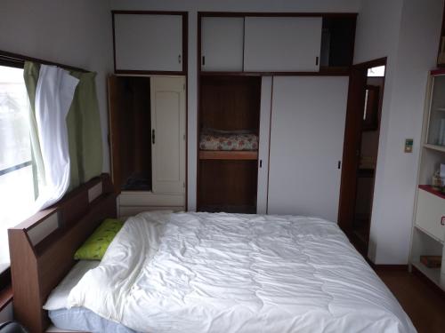 a bedroom with a bed with white sheets and cabinets at コウノトリの里の宿 in Fukiage