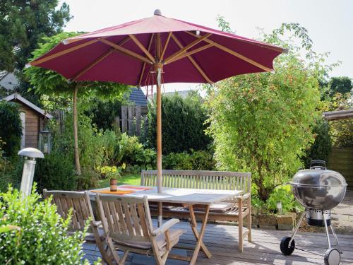 a patio table with an umbrella and a grill at Apartment with sauna in Merlsheim