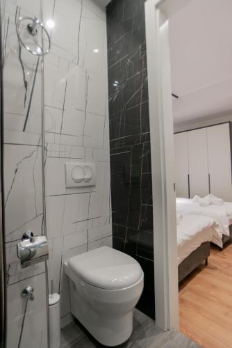 a small bathroom with a toilet and a bed at La Gioia Apartment in Tirana