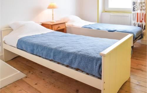 アロマンシュ・レ・バンにあるNice Home In Arromanches-les-bains With 2 Bedroomsのツインベッド2台、テーブル、ランプが備わる客室です。