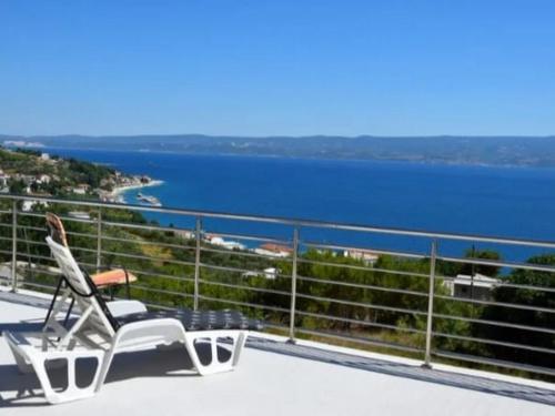 une chaise blanche assise sur un balcon donnant sur l'eau dans l'établissement Apartment Mila, à Jesenice