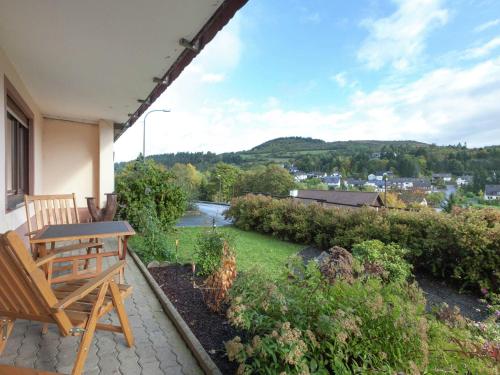 un patio con tavolo e panca sul balcone di Mountain view Apartment in Mullenborn Garden a Gerolstein