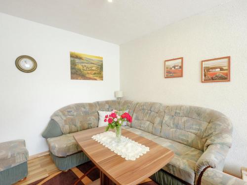 ein Wohnzimmer mit einem Sofa und einem Tisch mit Blumen in der Unterkunft Holiday home in Hasselfelde with private terrace in Stiege