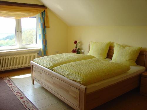 a bedroom with a bed with yellow sheets and a window at Cosy Apartment in Wilsecker near the Forest in Kyllburg