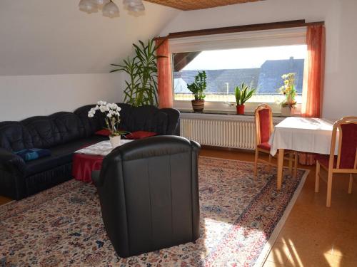 uma sala de estar com um sofá, uma mesa e uma janela em Cosy Apartment in Wilsecker near the Forest em Kyllburg