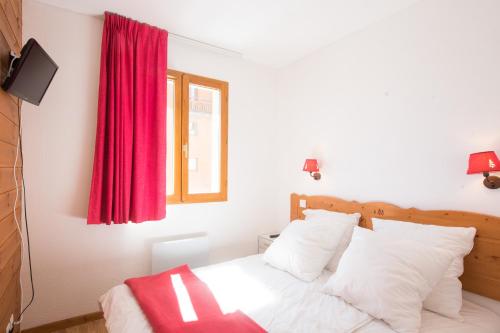une chambre avec un lit avec un rideau rouge dans l'établissement le hameau des ecrins, à Puy-Saint-Vincent