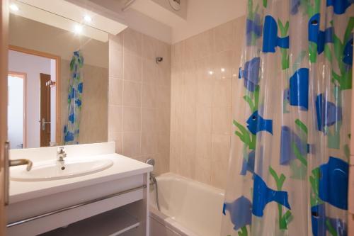 La salle de bains est pourvue d'un lavabo, d'une baignoire et d'un rideau de douche. dans l'établissement le hameau des ecrins, à Puy-Saint-Vincent