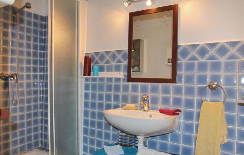 a blue tiled bathroom with a sink and a mirror at 2 Bedroom Lovely Apartment In St Bonnet En Champsaur in Saint-Bonnet-en-Champsaur