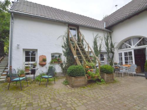 ein weißes Haus mit Stühlen und einer Treppe darin in der Unterkunft Romantic ground floor apartment for 2 people in Immerath