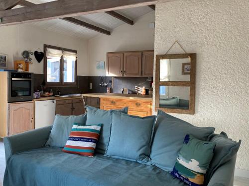 a living room with a blue couch and a kitchen at Maison Vert d'Eau in Grand-Village-Plage