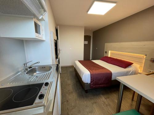 a room with a bed and a kitchen with a sink at La Tour D'ivoire in Reignier