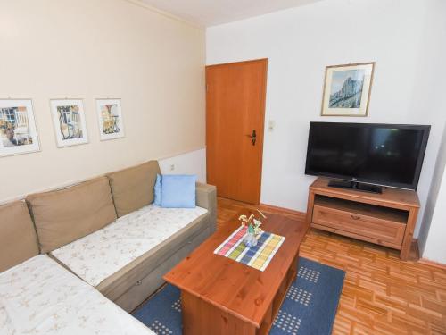 ein Wohnzimmer mit einem Sofa und einem Flachbild-TV in der Unterkunft Fine Apartment in Ruhpolding with Swimming Pool in Ruhpolding