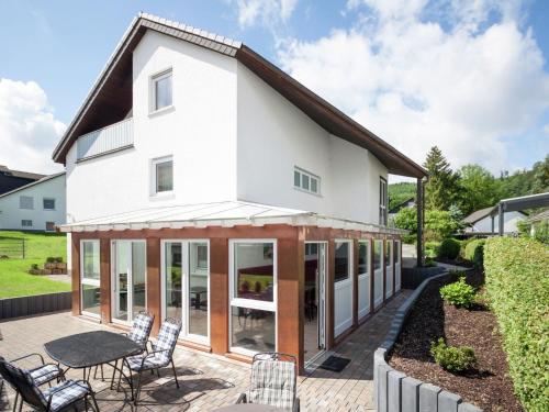a white house with glass doors and a patio at Enchanting Holiday Home in B defeld with Terrace in Schmallenberg