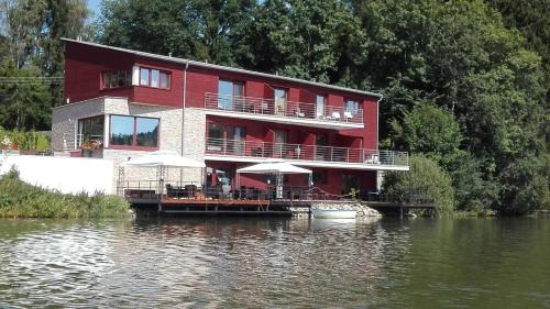 a red house on a dock in the water at Penzion Ratmírák in Malý Ratmírov