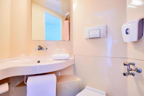 a bathroom with a sink and a toilet and a mirror at Premiere Classe Lille Nord Roncq in Roncq