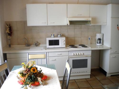 アッテンドルンにあるAttractive Apartment in Silbecke with Gardenのキッチン(白いキャビネット、テーブル、電子レンジ付)