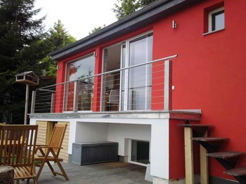 ein rotes Haus mit einem Balkon und einer Terrasse in der Unterkunft Bright holiday home in Schnett with private garden in Schnett