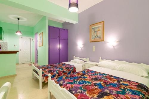 two beds in a room with purple and green walls at Ni-Mar Studios & Apartments in Lithakia