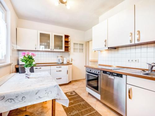 a kitchen with white cabinets and a table with a vase of flowers at Ferienhaus in Medebach nahe Skigebiet in Medebach