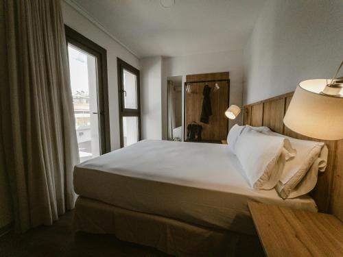 a bedroom with a bed with a window and a lamp at Petit Palace Vargas in Seville