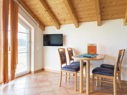 a dining room with a table and chairs and a tv at Alluring Farmhouse in Ingenried with Solarium in Bernbeuren