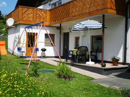 ein Haus mit einer Terrasse mit einem Sonnenschirm in der Unterkunft Apartment in Lechbruck Bavaria with garden in Lechbruck