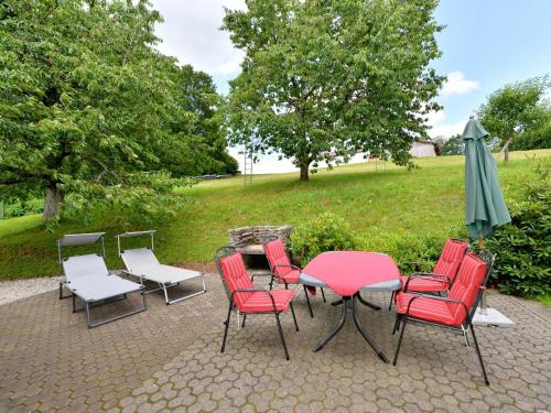 een patio met een tafel en stoelen en een parasol bij Holiday home with sauna near a ski resort in Drachselsried