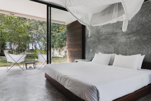 a bedroom with a white bed and a large window at Costa Lanta - Adult Only in Ko Lanta