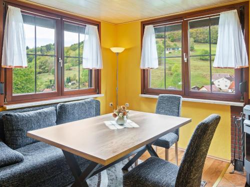 ein Esszimmer mit einem Tisch, Stühlen und Fenstern in der Unterkunft Holiday home in Thuringia near the lake in Langenbach