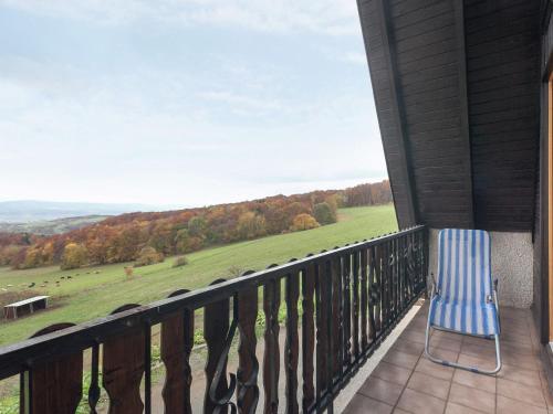 une chaise sur un balcon avec vue sur un champ dans l'établissement Holiday cottage with terrace near the Rennsteig, à Bad Liebenstein