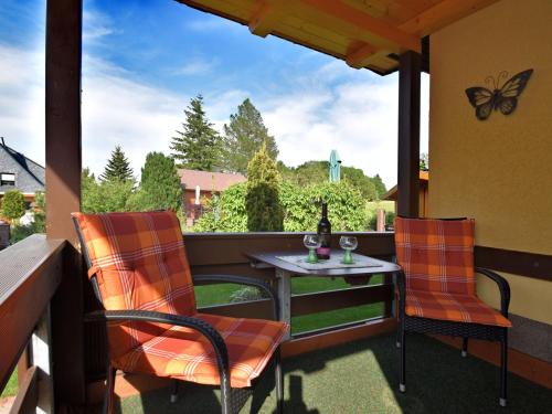 eine Terrasse mit 2 Stühlen und einem Tisch mit einem Schmetterling darauf in der Unterkunft Holiday home near the Schwarza Valley in Grossbreitenbach