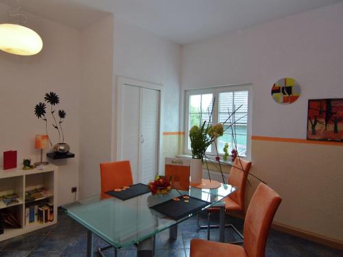 un soggiorno con tavolo in vetro e sedie arancioni di Romantic apartment in Ilmenau a Langewiesen