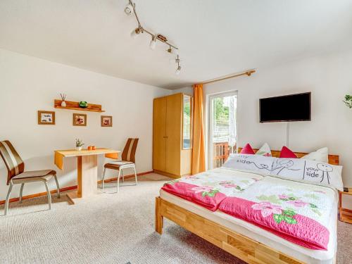 Schlafzimmer mit einem Bett und einem Tisch mit Stühlen in der Unterkunft Holiday home with garden in Langenbach