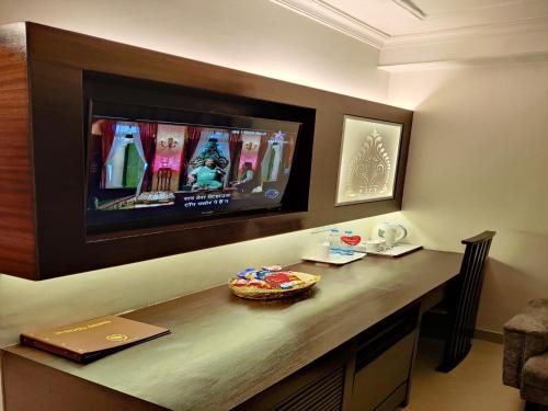 a room with a table with a television on a wall at The Samilton in Kolkata