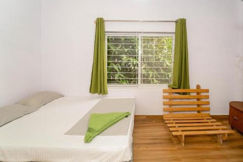 a bedroom with a bed and a window and a chair at Nest Holidays Homestay in Kaglipur