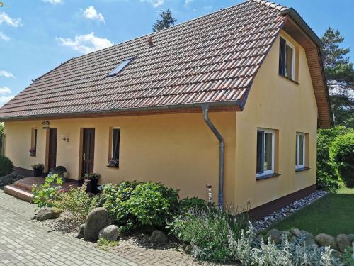 una pequeña casa amarilla con techo de baldosa en Spacious appartment in Wilhelmshof near Lake, en Wilhelmshof