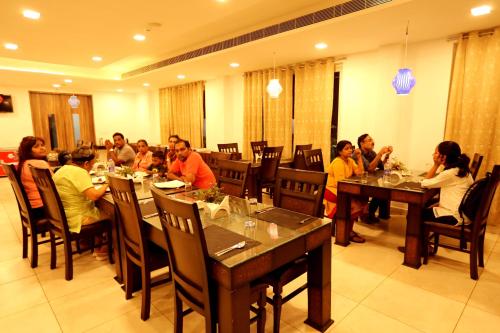 a group of people sitting at tables in a restaurant at Hotel Queens Inn Velankanni in Velānganni